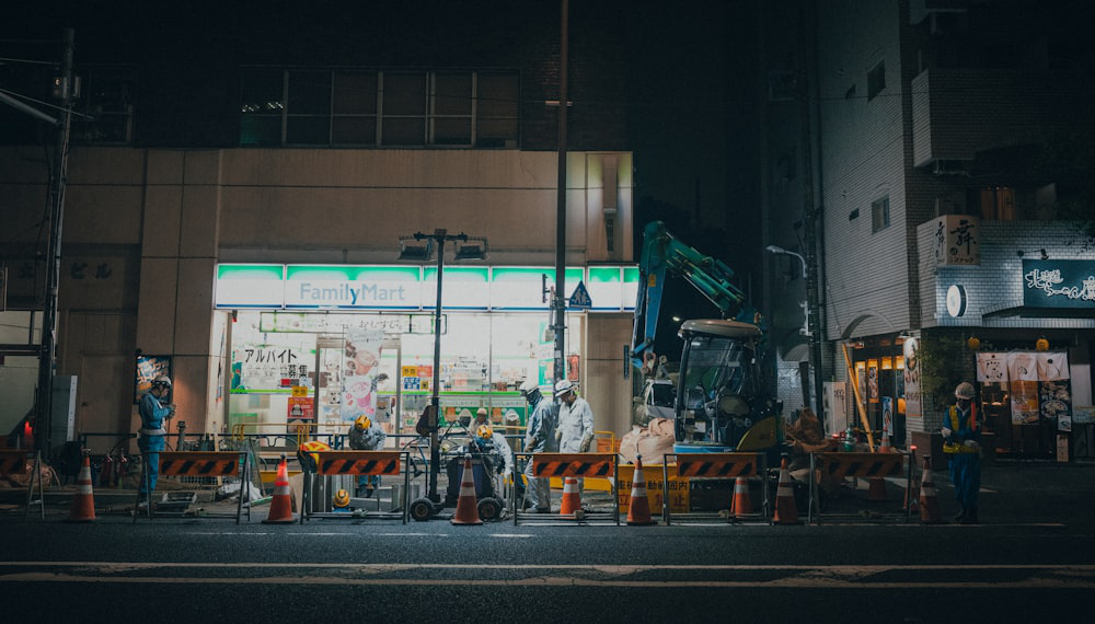 Construction workers in hard hats and vests working on a site at night.