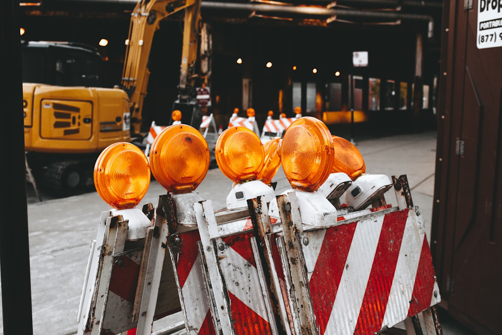 Orange warning lights on top of red and white metal construction barricades