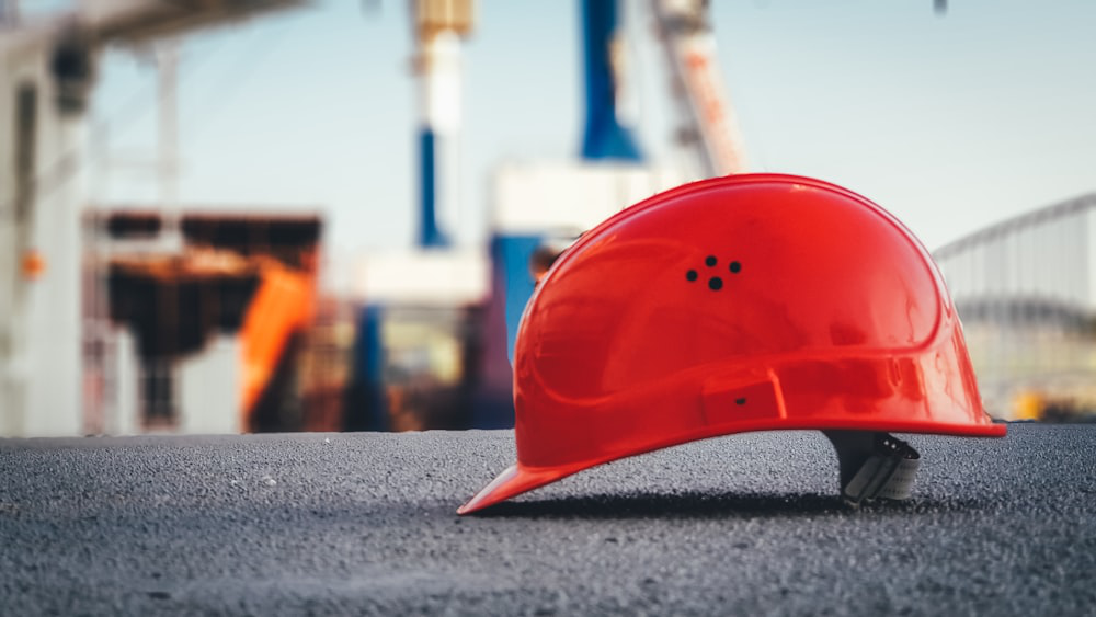 Red hard hat lying on the pavement, potential safety hazard on construction site